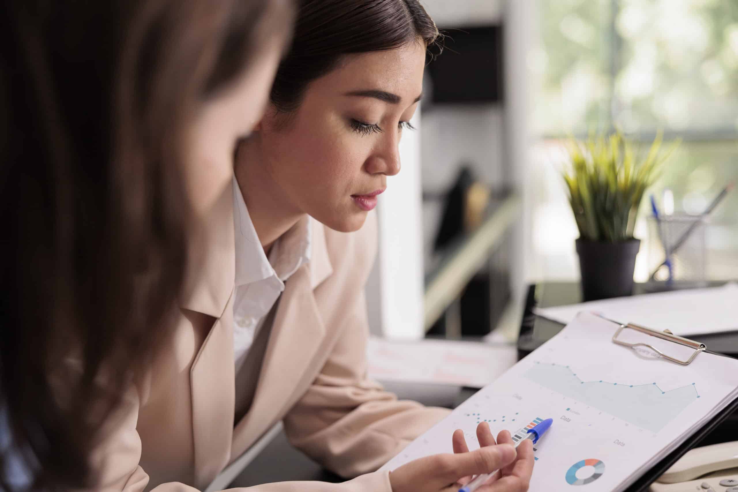 Employees analyzing financial report statistics on clipboard, woman pointing at charts on documents. Start up workers planning business strategy, discussing company research results