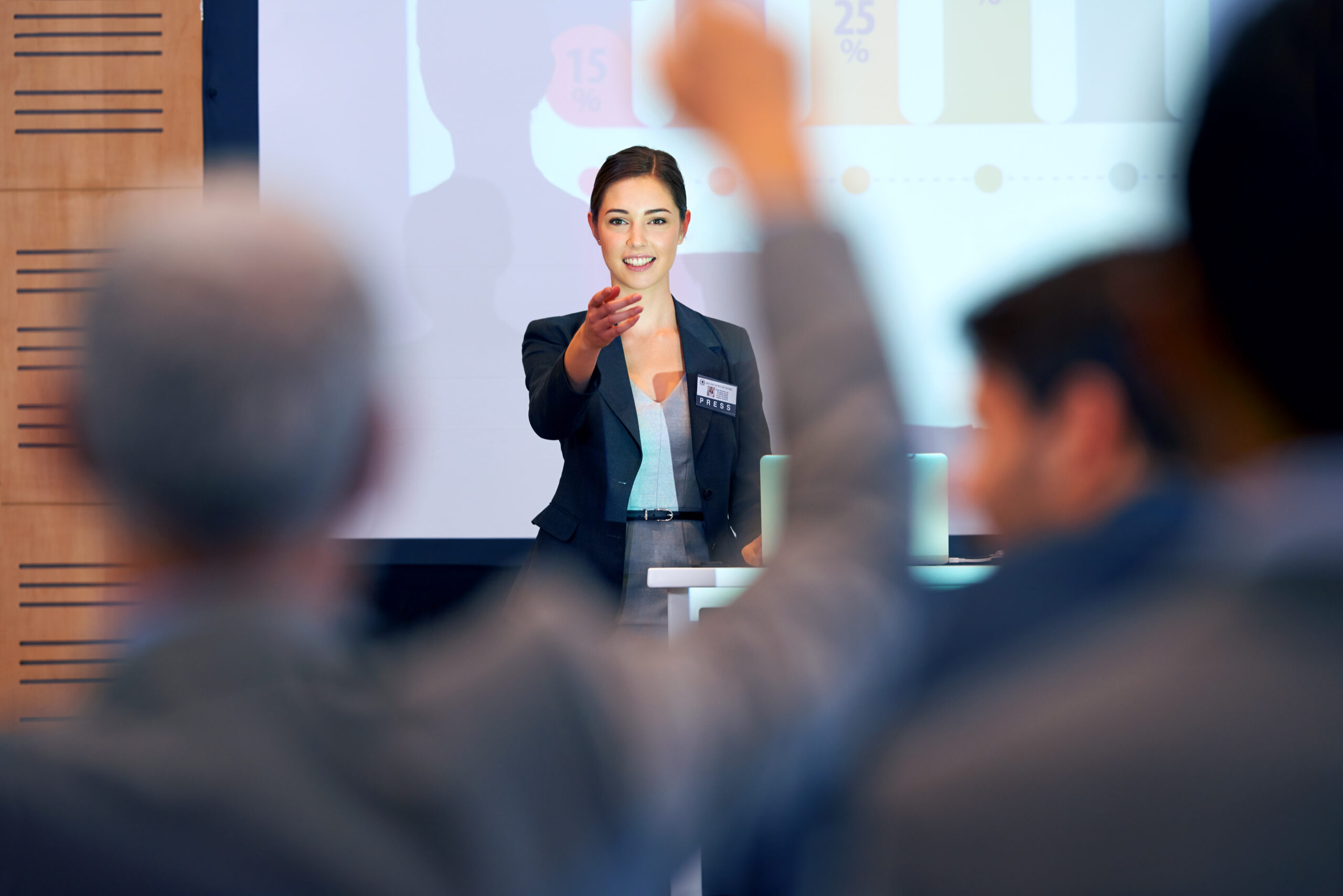 A portrait of a businesswoman gesturing while giving a presentation at a press conference