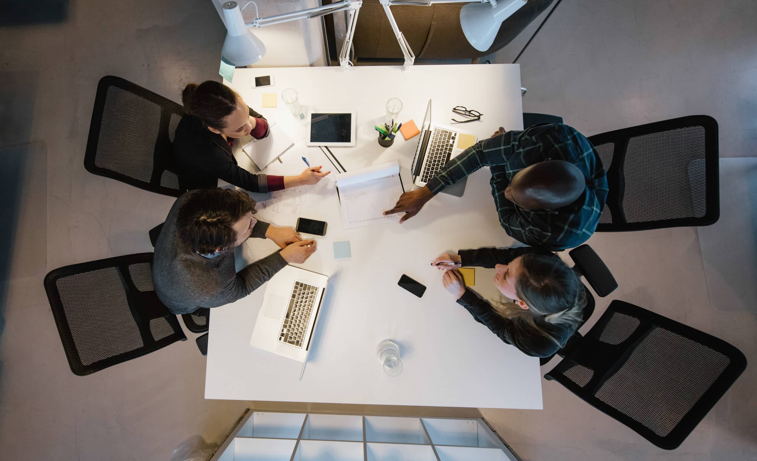 Overhead view of diverse team analyzing data while sitting at office. Multiracial business people in a meeting working on new project.